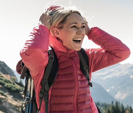 A women out hiking in the mountains happy and energized knowing she is staying healthy. 