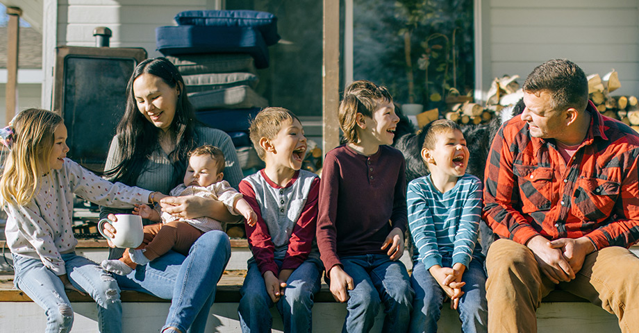 A couple with 5 kids sitting outside enjoying the weather.