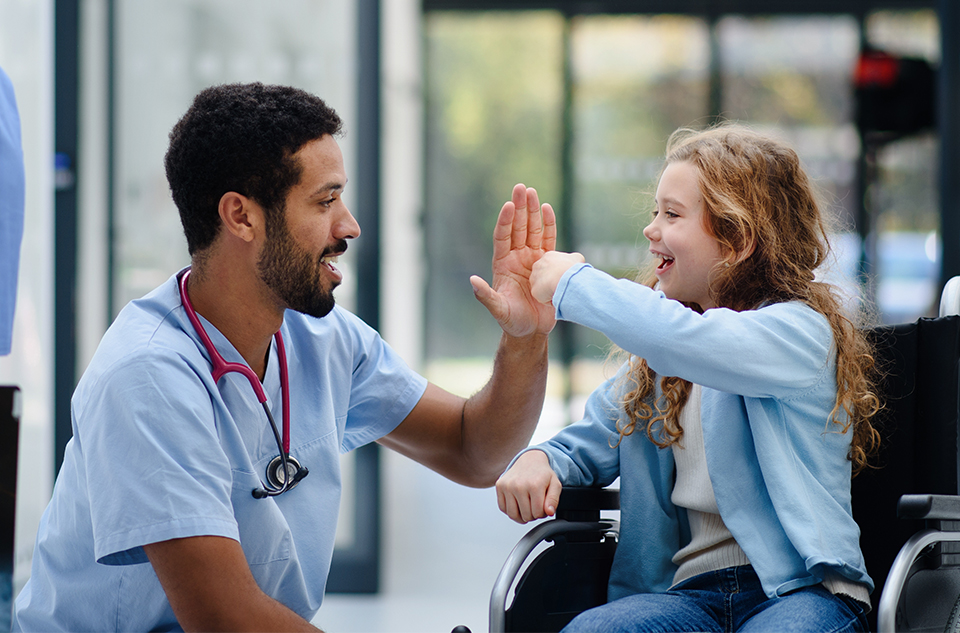 A doctor giving a child in a wheelchair a high five