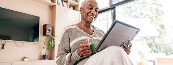 Woman with coffee cup looking at tablet