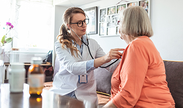 Doctor using stethoscope on womans chest