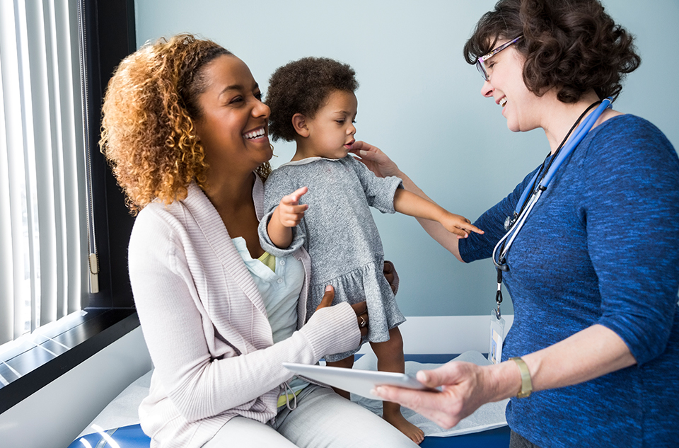 A mother holding her child while the doctor gives the child an exam